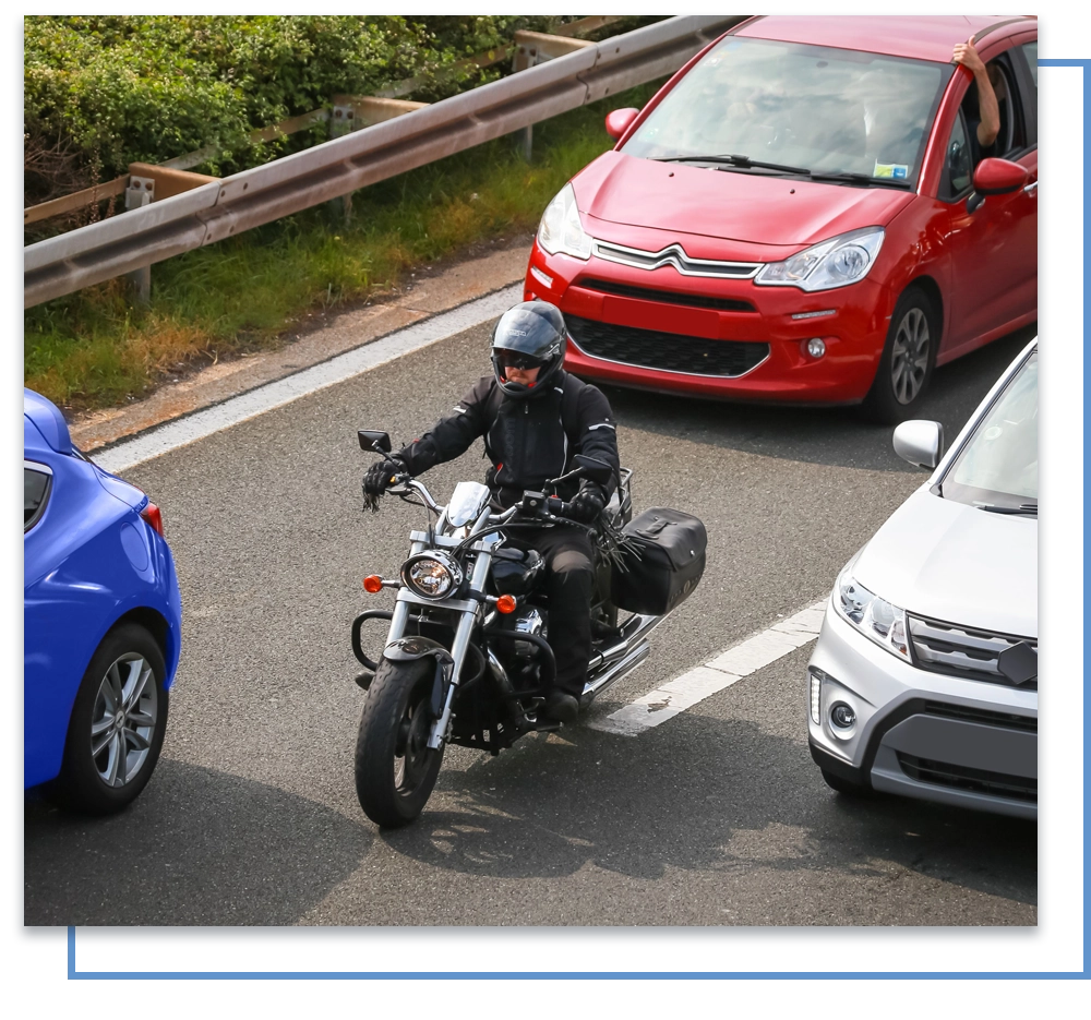 Motorcycle surrounded by cars on the road