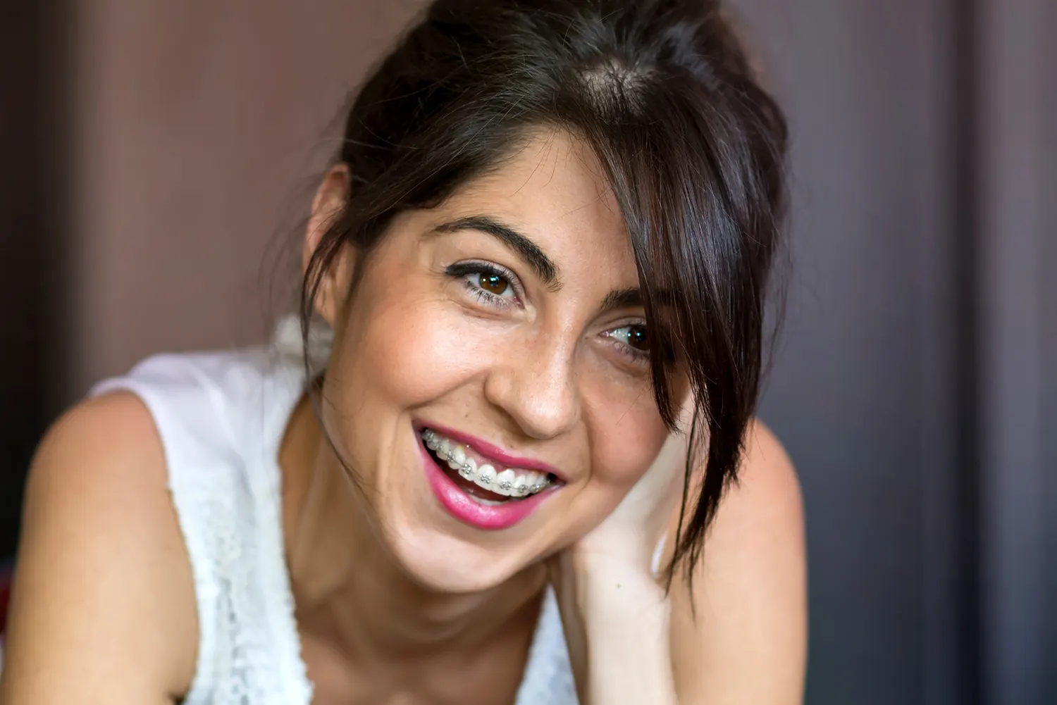 dark haired woman with braces smiling