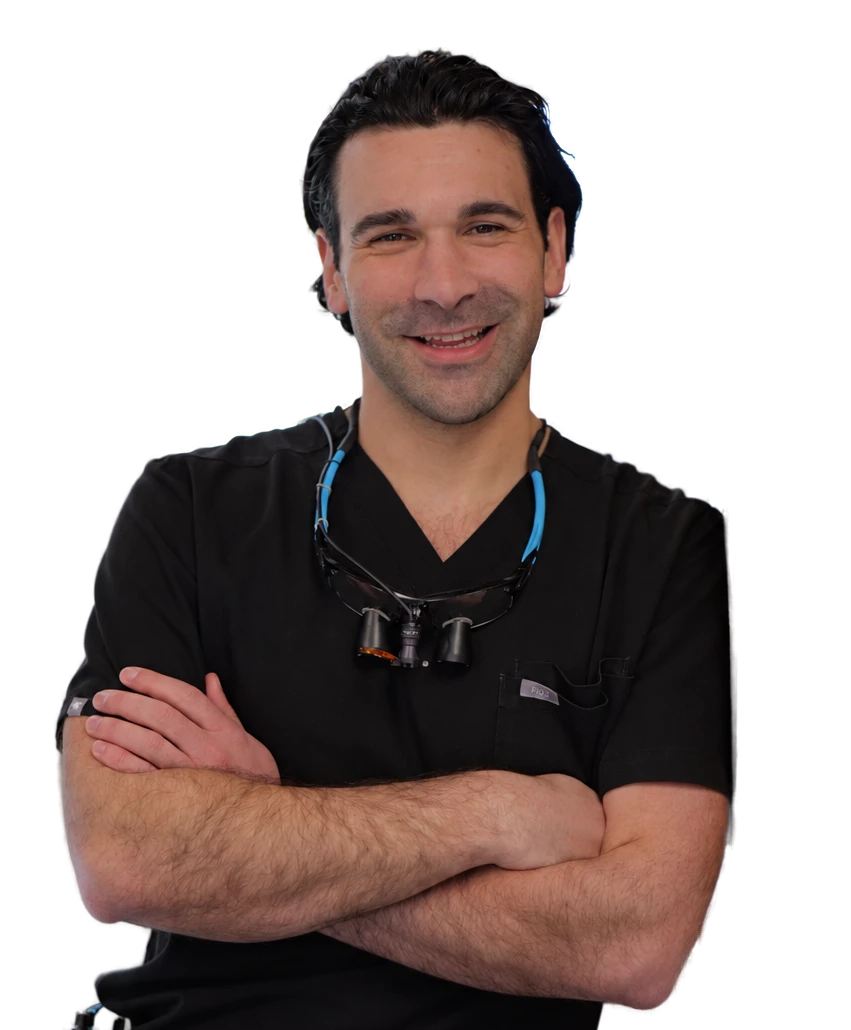 Dr. Kameron Tauber, pediatric dentist at Little Spurs, smiling with his arms crossed